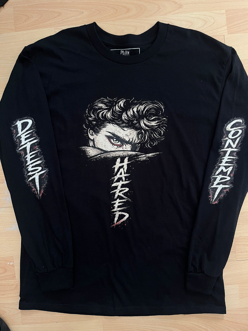 Black HATRED t-shirt with white graphic design and text on a wooden surface